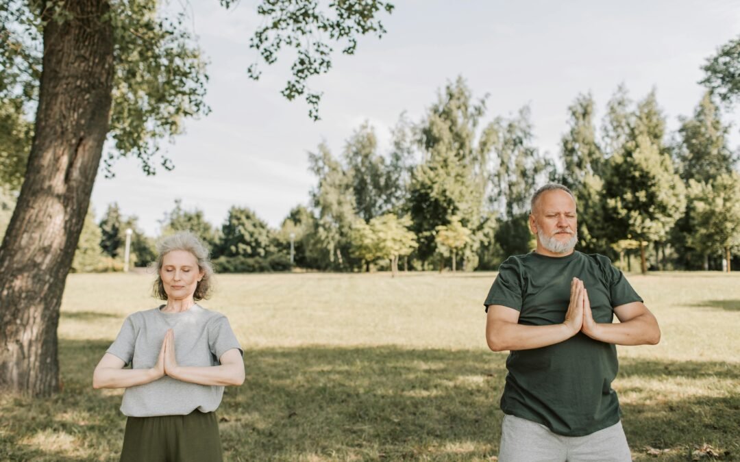 Image of a man and women meditating in a park